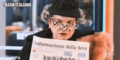 a woman wearing glasses and a black hat is reading a newspaper that says trash italiano