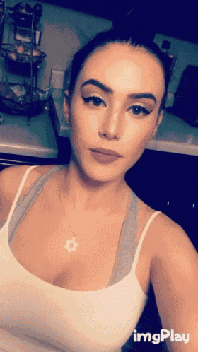 a woman in a white tank top is taking a selfie with imgplay written on the bottom