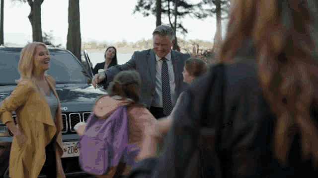 a man in a suit and tie stands in front of a jeep with a license plate that says 206