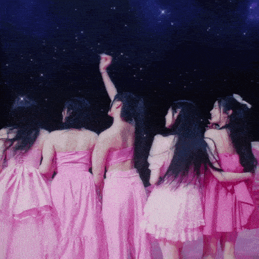 a group of girls in pink dresses are standing in a circle