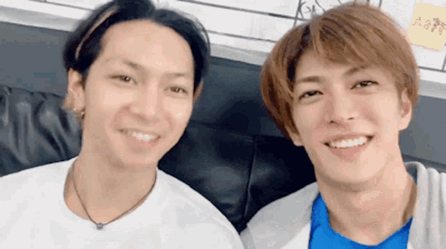 two young men are posing for a picture together and one is wearing a blue shirt
