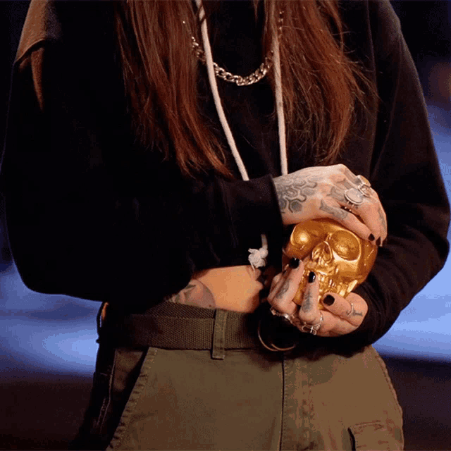 a woman holding a gold skull in her hands
