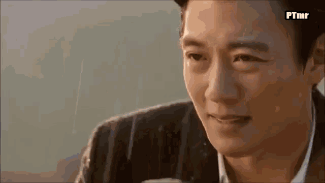 a close up of a man 's face with rain drops on his face .