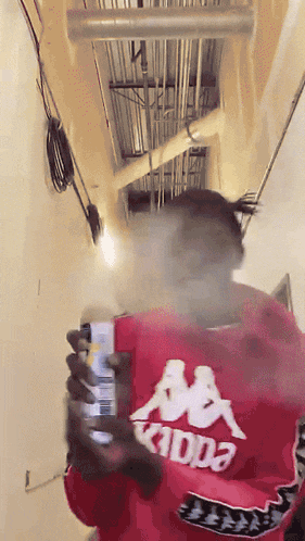 a man in a red kappa shirt is smoking a cigarette