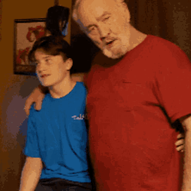 a man in a red shirt is standing next to a young boy in a blue shirt