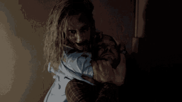 a woman holds a man 's head in her arms in a dark room