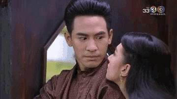 a woman is kissing a man on the cheek while they are sitting next to each other .