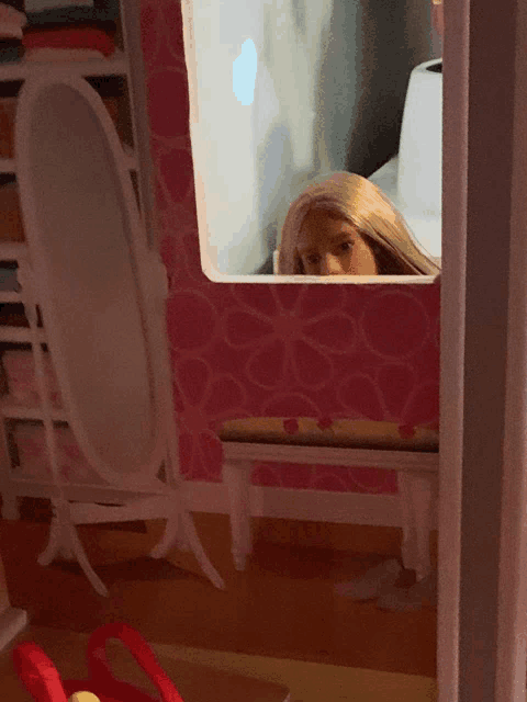 a doll is peeking out of a window in a doll house