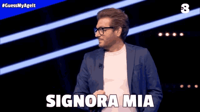 a man in a suit and glasses says signora mia on a stage