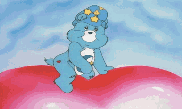 a care bear wearing a blue hat with stars on it is sleeping on a red heart