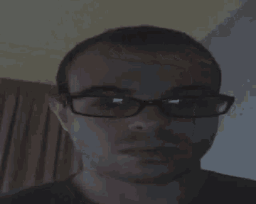 a man wearing glasses and a black shirt is looking at the camera