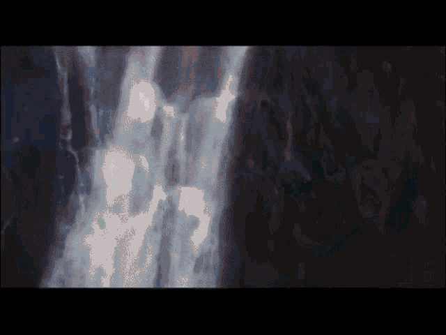 a waterfall with a dark background and a few white spots