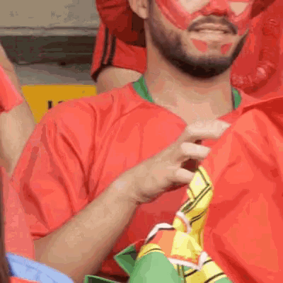 a man wearing a red mask and a red shirt is holding a yellow and black scarf