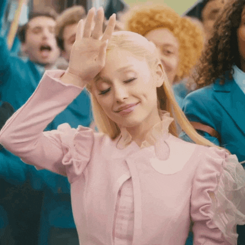 a woman in a pink dress is smiling and waving her hand