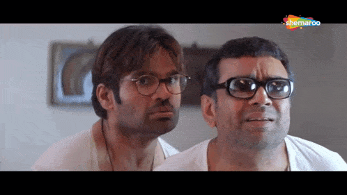 two men wearing glasses are looking at each other in a screenshot from a shemaroo channel