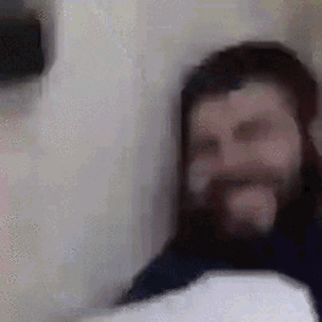 a man with a beard is sticking his tongue out in a blurry photo .