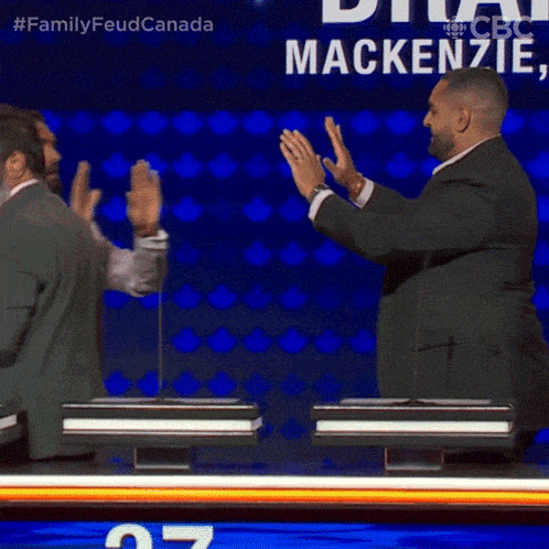 two men giving each other a high five in front of a mackenzie sign