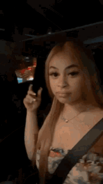 a woman is sitting in the driver 's seat of a car holding a seat belt .