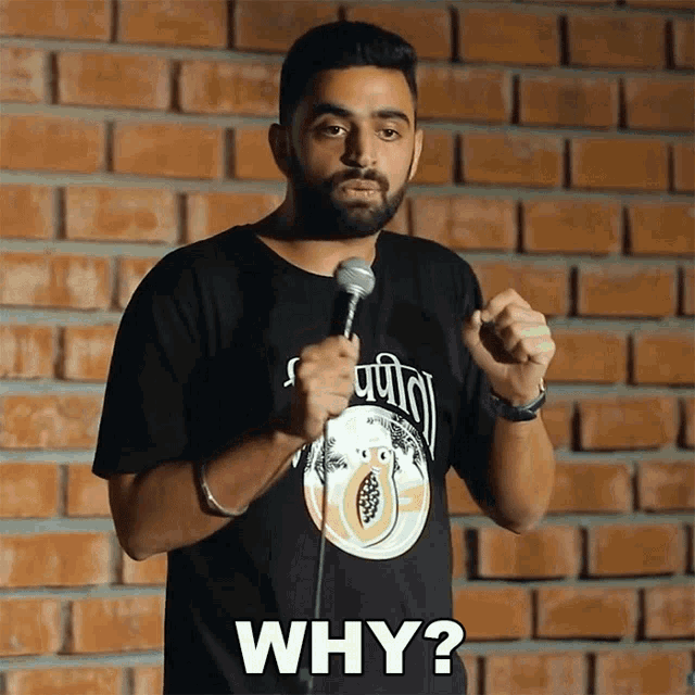 a man in a black shirt is holding a microphone and saying why