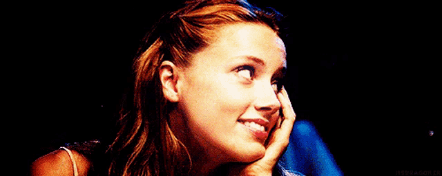 a woman covering her face with her hands and smiling .
