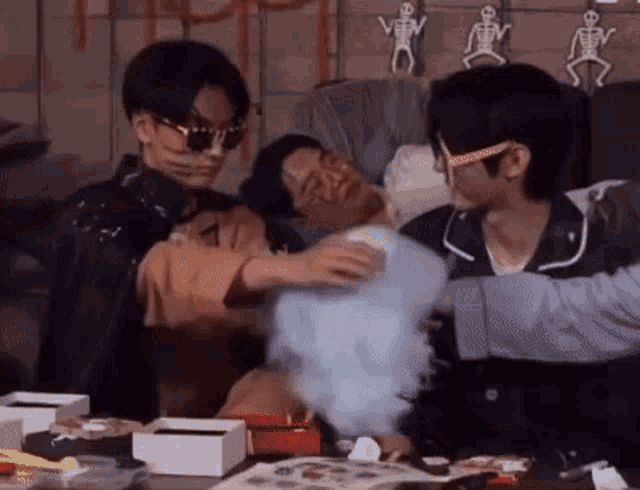 a group of young men are sitting around a table with cotton candy coming out of their mouths .