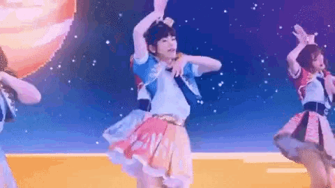 a group of girls are dancing on a stage and one of them is wearing a skirt that says ' n ' on it