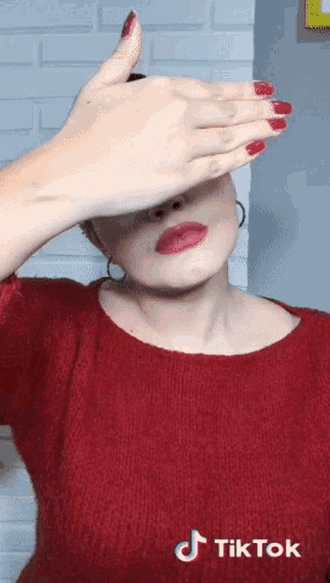 a woman in a red sweater is covering her face with her hand and a tiktok logo is visible