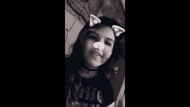 a girl with cat ears on her face is wearing a choker necklace .