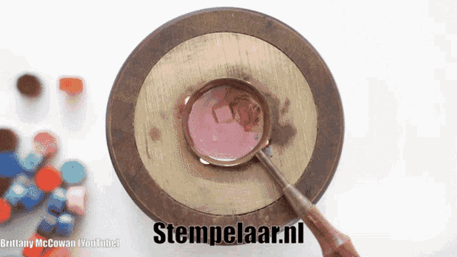 a magnifying glass is sitting on a wooden table with stempelaar.nl written on the bottom right