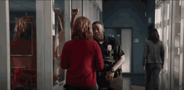 a police officer is talking to a woman in a hallway .
