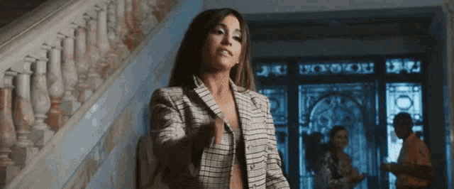 a woman in a plaid jacket stands in front of a staircase