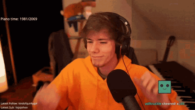 a man wearing headphones and an orange hoodie is sitting in front of a microphone with the date 1981/2069 on the bottom