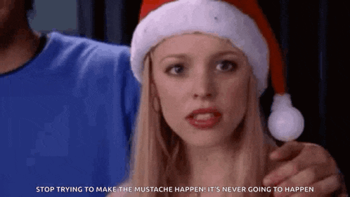 a woman is wearing a santa hat and holding a lollipop in her hand .