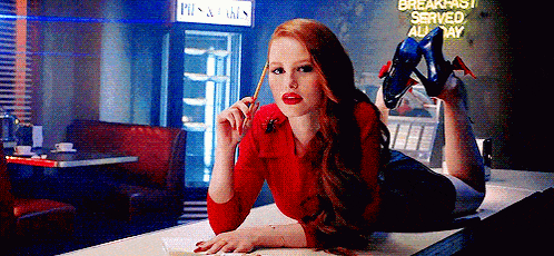 a woman is laying on a counter in a diner with her legs crossed and holding a pen .