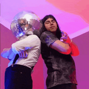 a man with a disco ball on his head stands next to another man holding a microphone