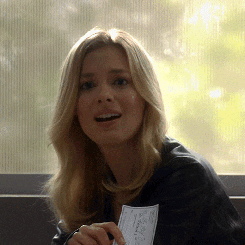 a woman in a black jacket holds a piece of paper that says " i 'm sorry "