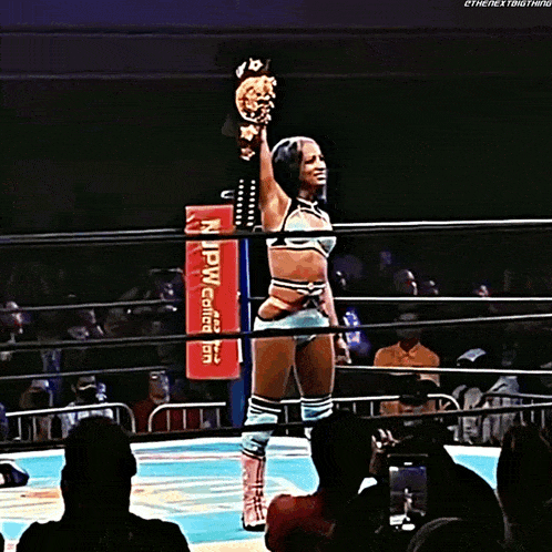 a woman in a wrestling ring holds up a trophy in front of a sign that says " npw collection "