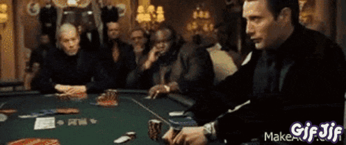a man in a black suit is playing poker with a gif that says gif jif