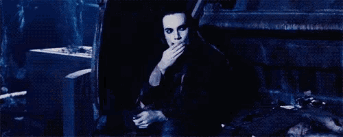 a man is sitting in front of a fire in the dark .