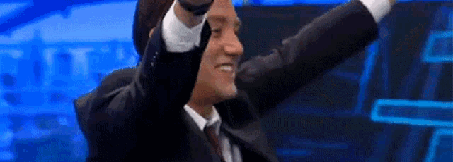 a man in a suit is raising his arms in the air .
