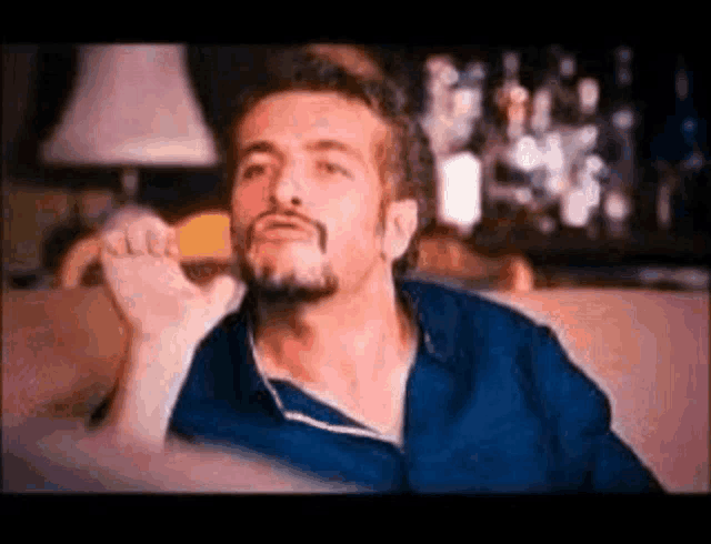 a man with a beard is sitting on a couch and making a funny face