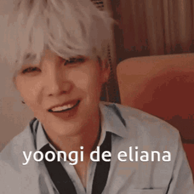 a young man with white hair is sitting in a chair with the words yoongi de eliana above him