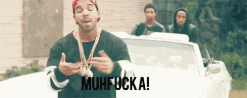 a man is standing in front of a white car with the words `` muhfuck a '' written on the screen .