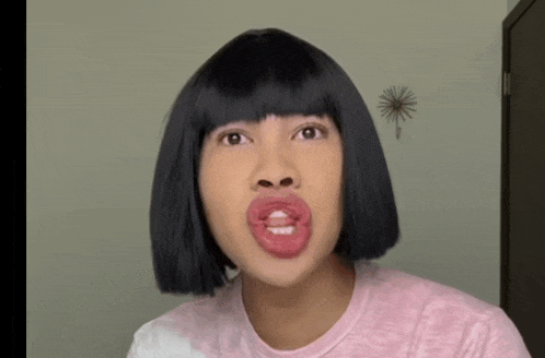 a woman wearing a wig and a pink shirt makes a face