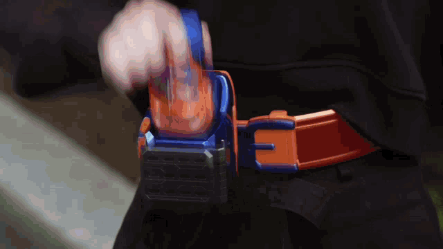 a person is wearing a belt with a blue and orange buckle with the letter e on it
