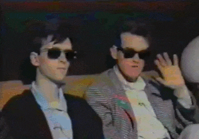 a group of men wearing sunglasses are sitting next to each other on a couch .