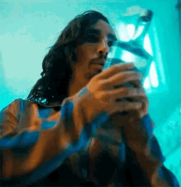 a man with long hair and a beard is holding a bottle of water .