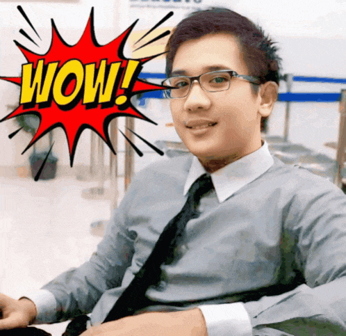 a man wearing glasses and a tie is sitting in front of a cartoon explosion that says wow