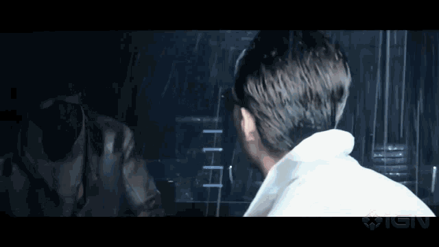 a man in a white shirt is talking to another man in a mask