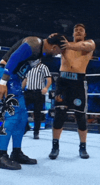 a wrestler with the word waller on his shorts is standing next to another wrestler